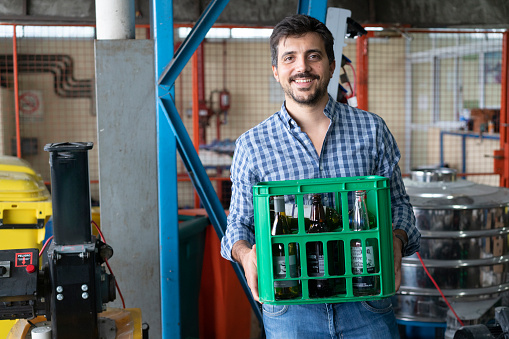 Portrait of a happy recycling center worker handling a crate with empty glass bottles