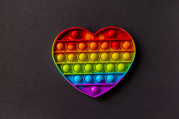 istock Colorful sensory toy fidget push pop it heart on black background 1333863036