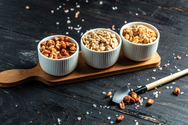 assorted peanuts with different seasonings for beer, on dark brown wooden background with copy space. snacks for beer. banner, menu, recipe - beer nuts imagens e fotografias de stock