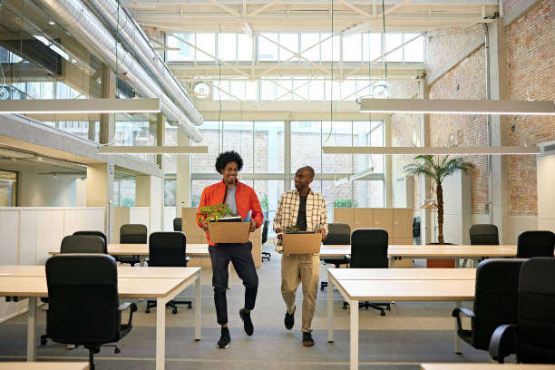 Black Businessmen in 20s and 30s Moving Into New Office Full length front view of smiling men in casual clothing walking towards camera carrying cardboard boxes in modern industrial-style work environment. belongings stock pictures, royalty-free photos & images