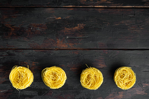 Durum wheat semolina homemade egg pasta tagliarini set, on old dark  wooden table, top view flat lay, with copy space for text
