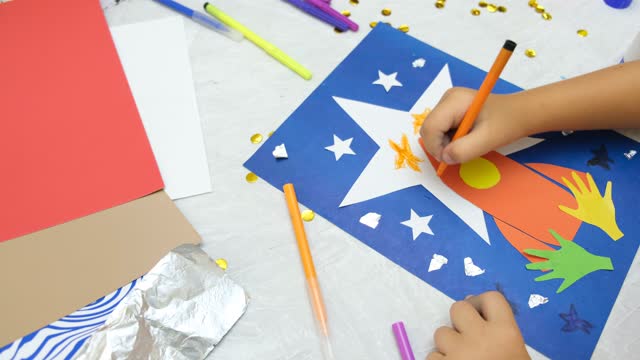 Child making rocket and stars from paper. Creative children play with craft