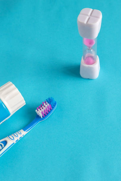 istock Blue background with a toothbrush and hourglass, kids brushing time 1333884990