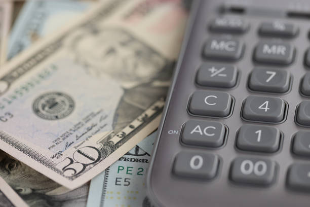 Gray calculator lying on dollar bills closeup. Annual tax payment concept