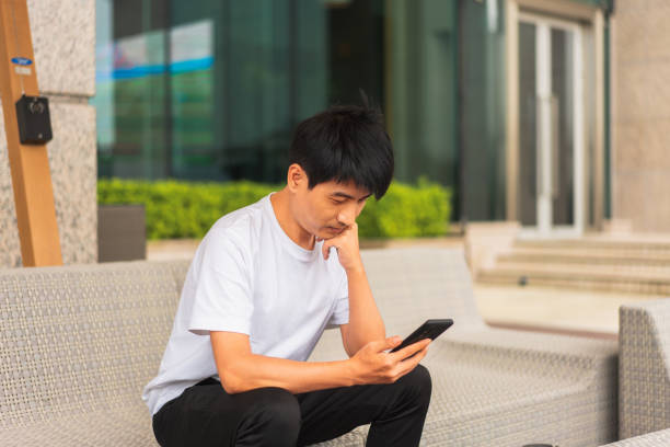 istock An Asian man sitting on a chair and using a smartphone 1333897966