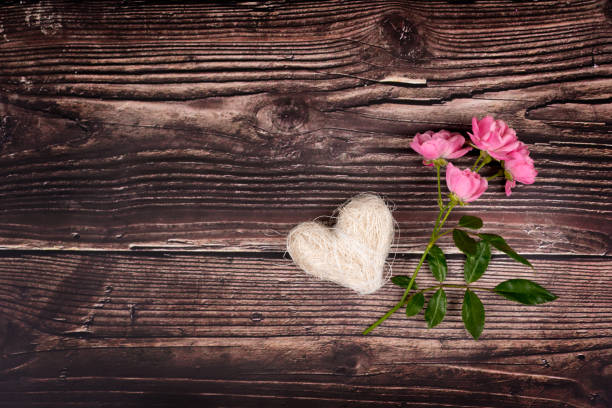 Branch of rose with heart on a brown table