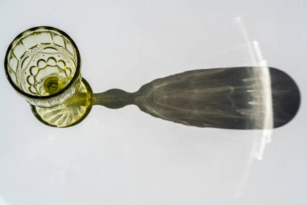 istock Green glass goblet with water. Abstract shadow pattern on white background. Texture for the background 1333903942