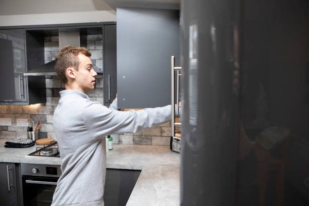 istock Male university student reaching into a kitchen cabinet 1333907124