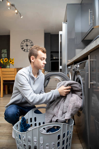 istock Male university student loading towels into a washing machine 1333907210