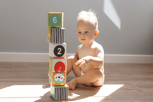 cute little boy playing at home with colorful cubes in the sunlight