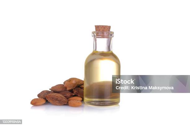 Apricot Seed Oil In A Glass Bottle Next To Apricot Bones On A White Isolated Background Stock Photo - Download Image Now