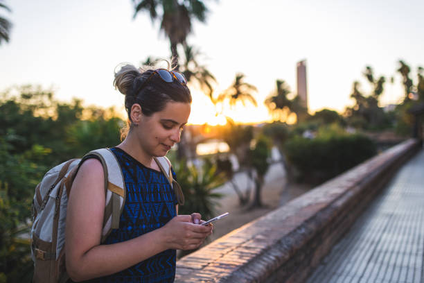 istock Smiling young woman using smartphone at sunset 1333913968