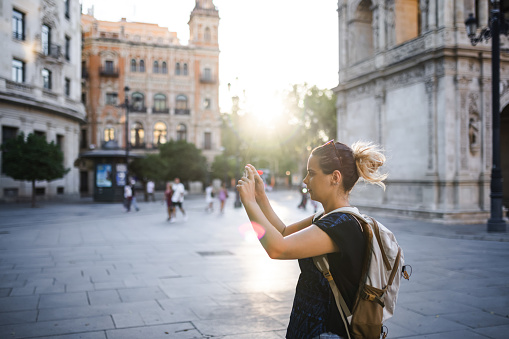 Woman photographing city at sunset