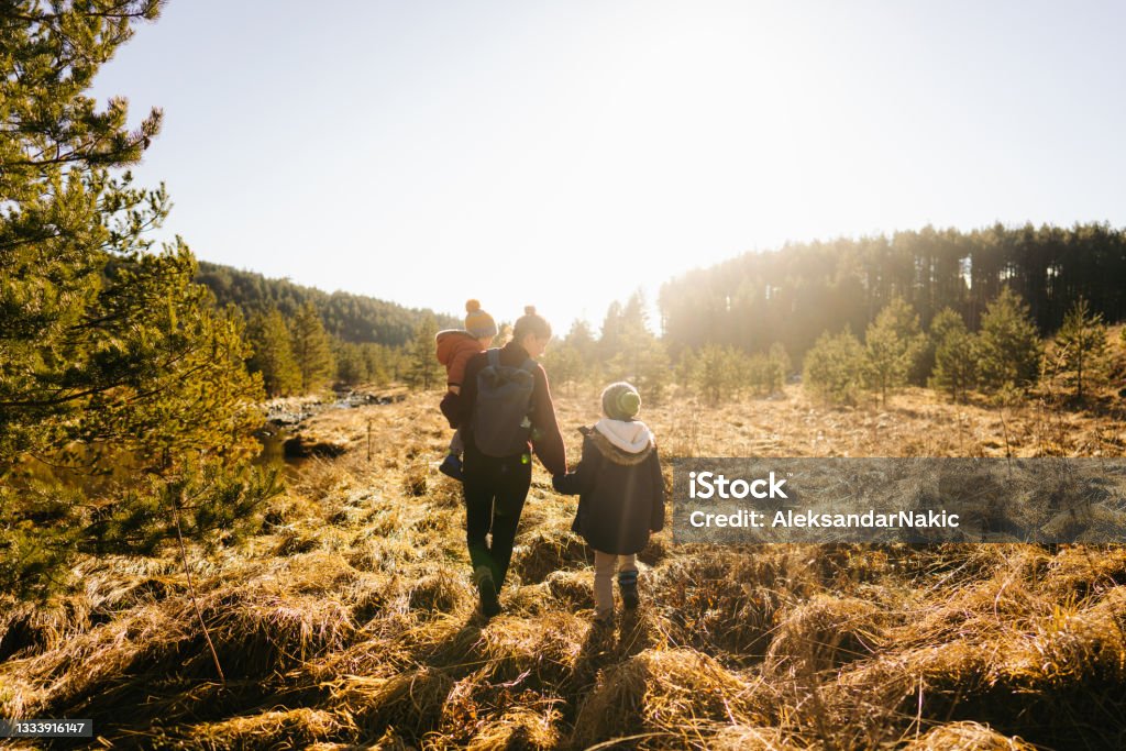 Exploring beautiful outdoors together Photo of young mother setting the standards for a happy and healthy life - by taking her children to a winter walk, on a cold sunny day Mother Stock Photo