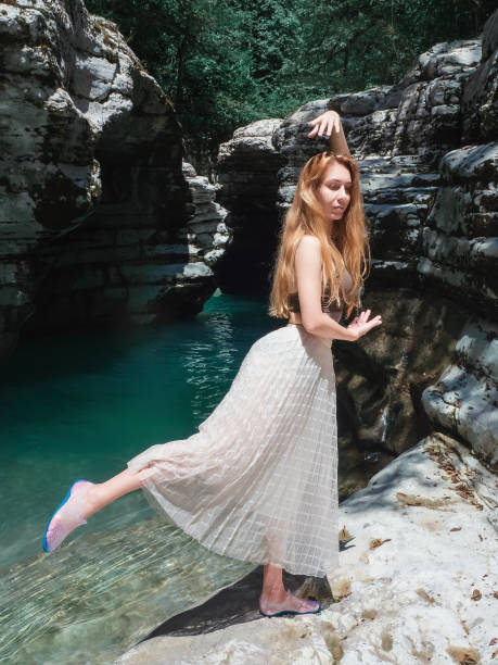 ein mädchen in einem tüllrock steht in einer schwalbenpose in der nähe eines türkisfarbenen flusses in einer felsigen umgebung - water rock landscape cliff stock-fotos und bilder