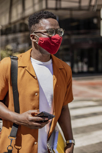 istock African-American young man walking and wearing protective face mask 1333918600