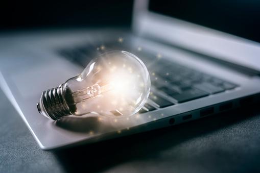 New idea illuminated light bulb on laptop concept for creativity and innovation