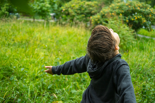 The boy enjoys nature.he runs across the field, spreading his arms to the sides
