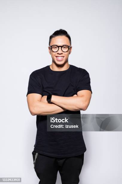 Cheerful Asian Young Man In Black Clothes Stock Photo - Download Image Now - Arms Crossed, Black Color, Gray Background