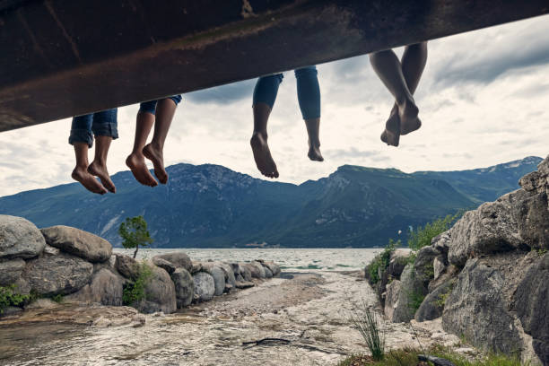 feet of family sitting n a bridge in limone sul garda - bridge people fun river imagens e fotografias de stock