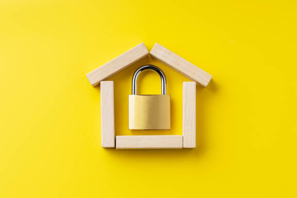 house symbol made by wooden blocks over yellow background with padlock inside. outer space. home protection and security concept stock photo