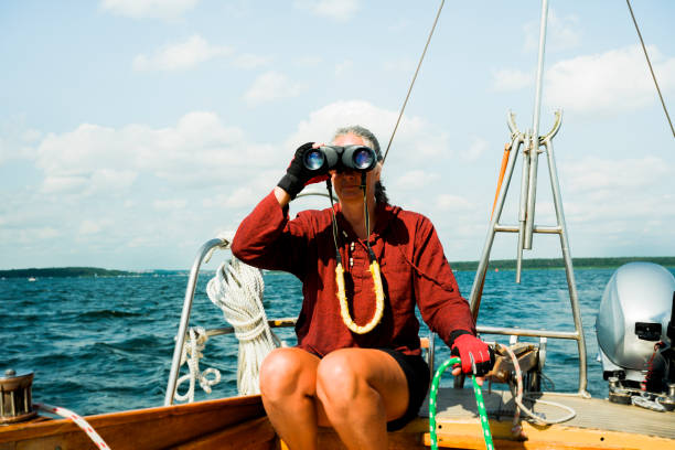 istock Active mature skipper woman looks through the binoculars while she sails her sailboat, Germany, adventure 1333926402