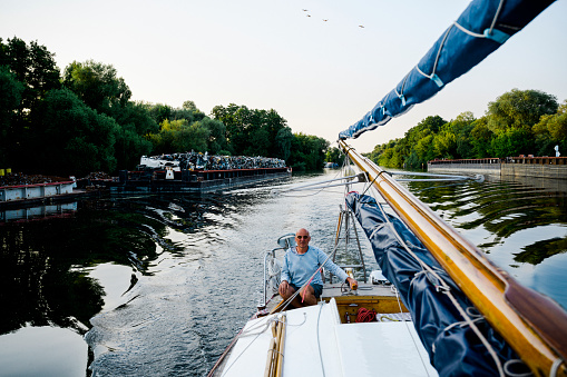 Active mature skipper on his sailboat travels in Canal, Germany, Brandenburg-State, Germany, adventure