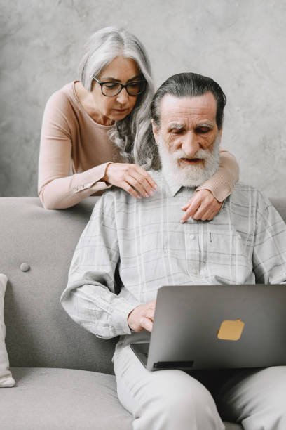 istock Senior couple sitting on couch with laptop 1333928545