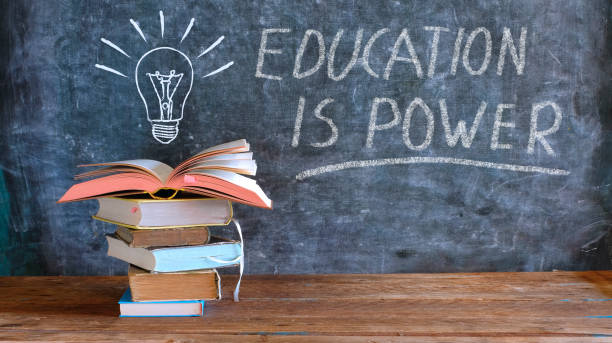 books and blackboard with drawing of a lightbulb and slogan education is power,learning,knowledge,back to school concept books and blackboard with drawing of a lightbulb and slogan education is power,learning,knowledge,back to school concept tradeshow photos stock pictures, royalty-free photos & images