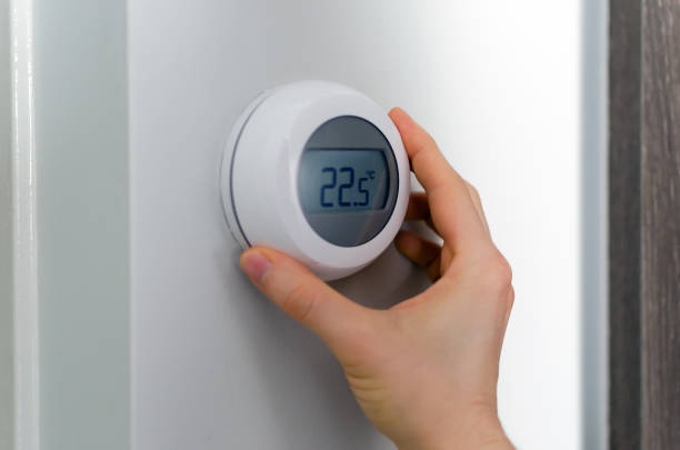 Hand is setting the room temperature with a thermostat stock photo