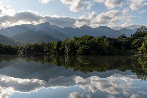 Beautiful view to green mountains and clouds reflected on lake in Guapiaçu, Rio de Janeiro, Brazil