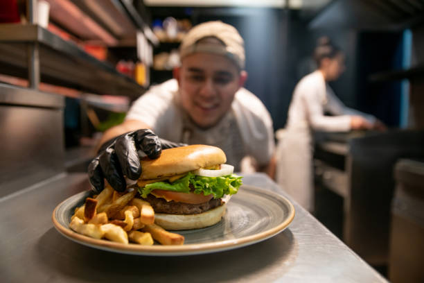 happy chef preparing burgers at a fast food restaurant - burger king imagens e fotografias de stock