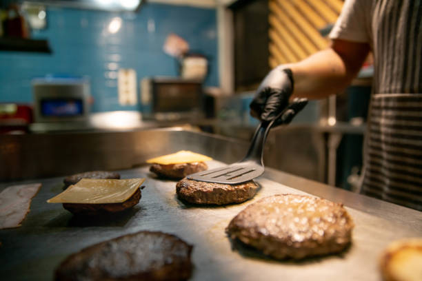 zbliżenie na szefa kuchni przygotowującego hamburgery w restauracji - cafeteria food service business zdjęcia i obrazy z banku zdjęć