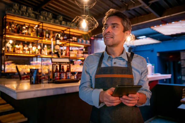 istock Happy waiter working at a restaurant and holding a tablet computer 1333944316
