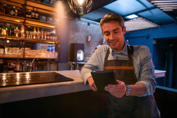 istock Happy waiter working at a restaurant and reading the menu on a tablet 1333944346