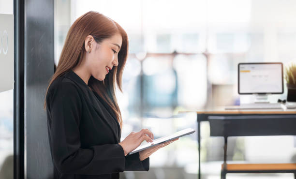 istock Successful businesswoman working on computer tablet while standing in her modern office room. 1333946336