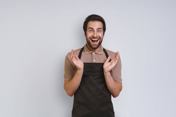 istock Excited young man in apron looking at camera and gesturing 1333946753