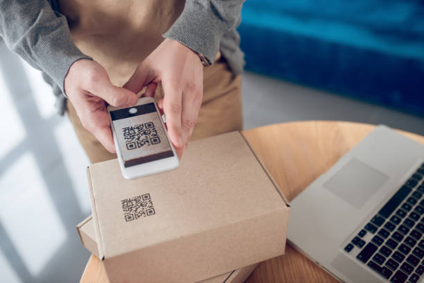 istock Male seller aiming his camera at the QR code on the cardboard box 1333948650