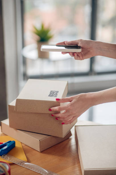 istock Female with red nails holding her smartphone over a cardboard box 1333948677