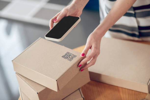 istock Female hands holding a gadget over the packaged box 1333948682
