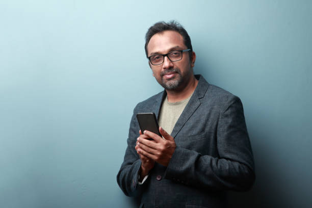 웃는 얼굴로 휴대 전화를 들고 있는 인도 인종의 남자 - men glasses blazer 40s 뉴스 사진 이미지