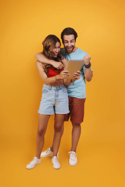 istock Full length of beautiful young couple using digital tablet and smiling 1333951867