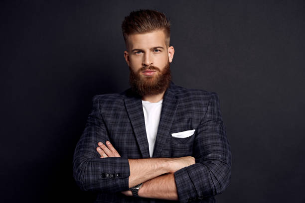 istock Handsome man keeping arms crossed and looking at camera while standing against grey background. 1333953198