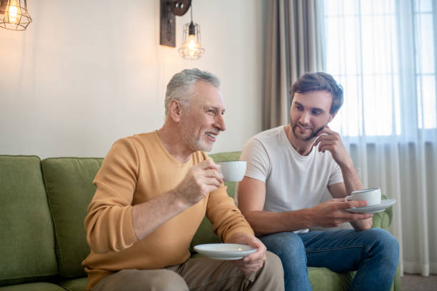 istock Father and son sitting next to each other and drinking tea 1333958444