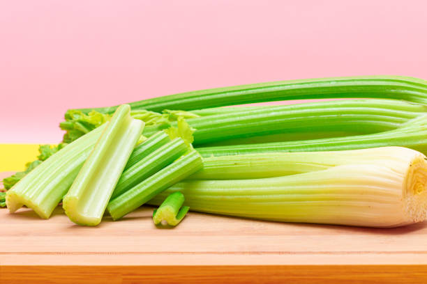 Fresh Celery Stem and Chopped Celery Sticks on Wooden Cutting Board. Vegan and Vegetarian Culture. Raw Food. Healthy Diet with Negative Calorie Content. Slimming Food