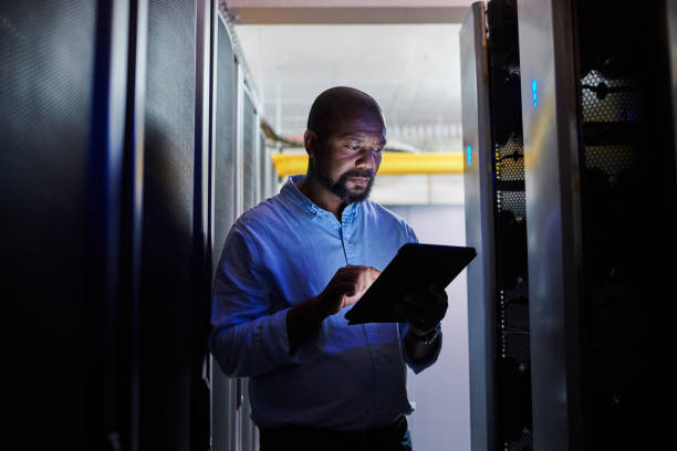 istock Shot of a male engineer using a digital tablet while working in a server room 1333959180