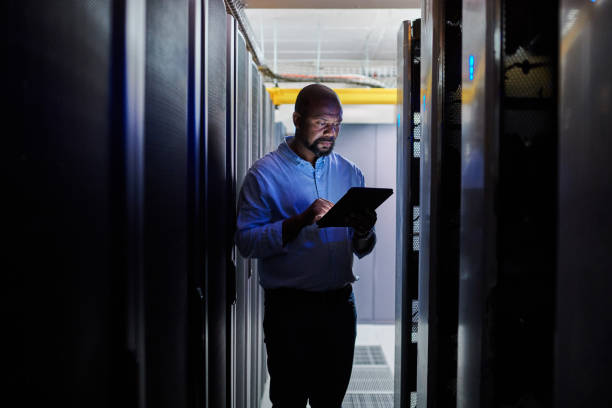 Shot of a male engineer using a digital tablet while working in a server room