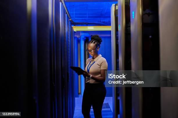 Shot Of A Young Female Engineer Using A Digital Tablet While Working In A Server Room Stock Photo - Download Image Now