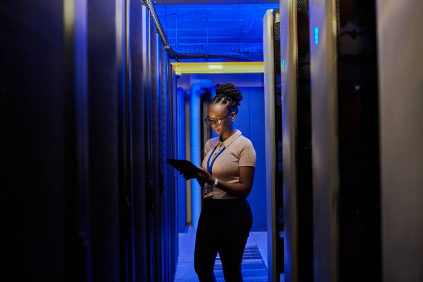 shot of a young female engineer using a digital tablet while working in a server room - computer network server repairing technology imagens e fotografias de stock