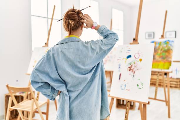 istock Young caucasian girl at art studio backwards thinking about doubt with hand on head 1333961859